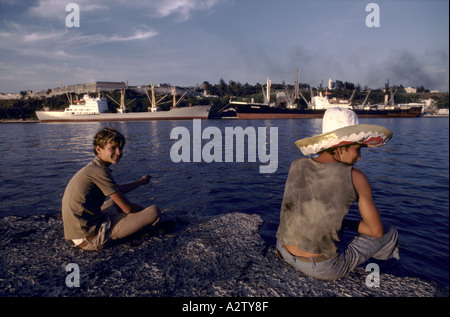 Two young men sitting by the port in Havana, Cuba Stock Photo