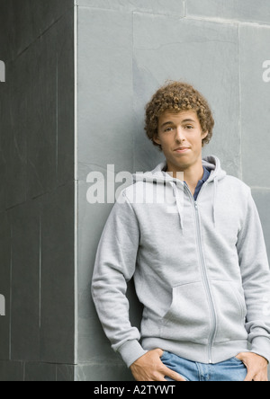 Young man standing with thumbs in pockets, looking at camera Stock Photo