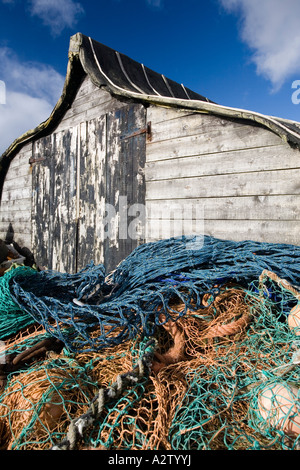 Upturned fishing boat used as a shed with fishing tackle and nets outside on Holy Island, Lindisfarne Stock Photo