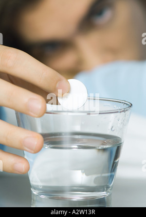 Man putting effervescent medicine into glass of water Stock Photo