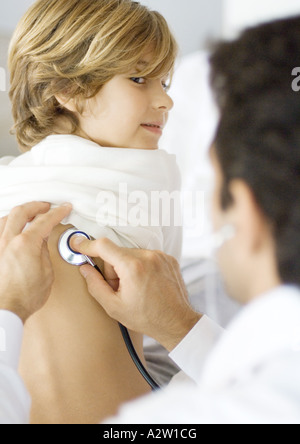 Doctor holding stethoscope to boy's back Stock Photo