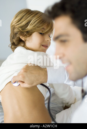 Doctor holding stethoscope to boy's back Stock Photo