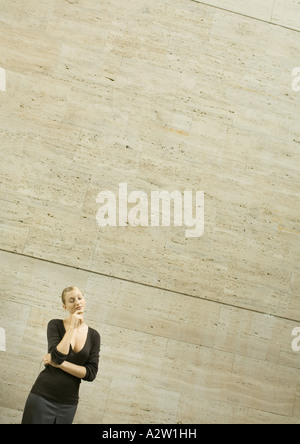 Woman standing with eyes closed and hand under chin Stock Photo