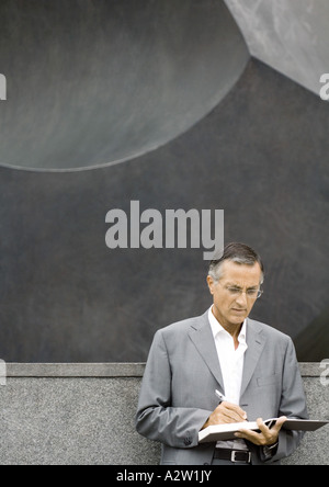 Businessman standing, writing in agenda Stock Photo