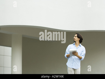 Man standing taking notes on pad of paper Stock Photo