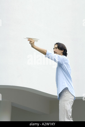 Man standing, aiming paper airplane Stock Photo