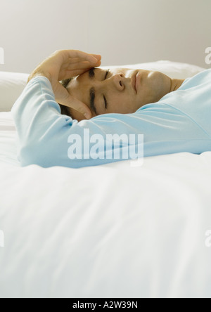 Man lying in bed, holding head Stock Photo
