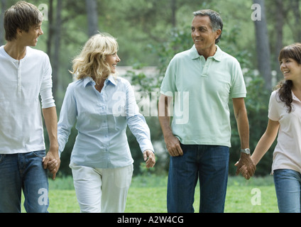 Mature couple walking, holding hands with teen grandchildren Stock Photo