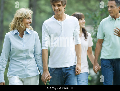 Mature couple walking, holding hands with teen grandchildren Stock Photo