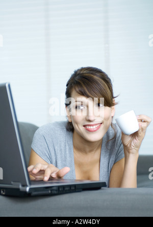 Woman drinking coffee and using laptop Stock Photo