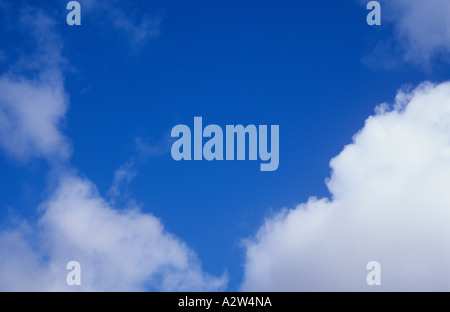 Puffy white cumulus clouds set against a clear blue sky Stock Photo