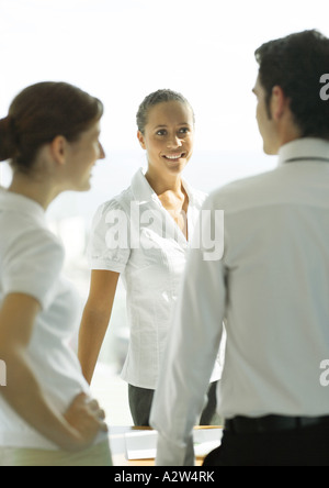 Three adults standing, talking in office Stock Photo