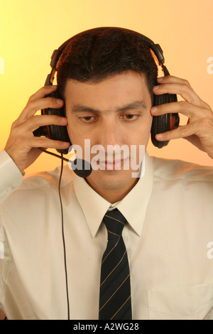 DPA 98279 South Asian Indian man Executive Dress in Shirt and tie listening music smily expression Model Release Number 623 Stock Photo