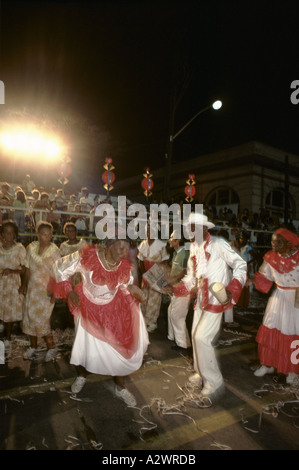 A couple dance in the street at night, lit by neon lighting, during the Santiago street carnival, Cuba. Stock Photo