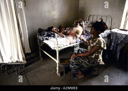 A woman sits by the bedside of another woman who is ill with laser fever. Segbwema Hospital, Sierra Leone, Africa Stock Photo