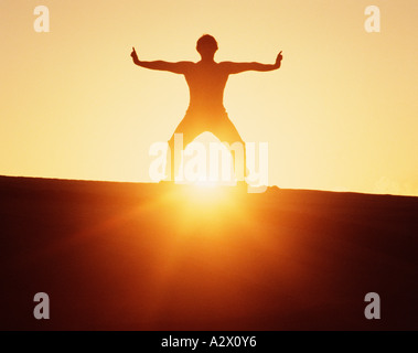 Silhouette of a man standing on a ridge at sunrise. Martial arts. Kung Fu. Stock Photo