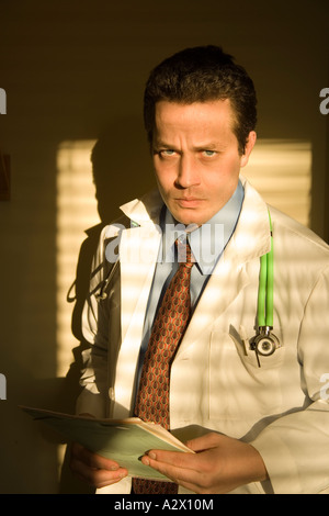 White male physician holds a patient chart in the doctors office, hospital of clinic. Stock Photo