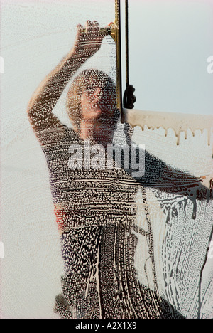 Window cleaner using squeegee. View through soapy glass. Stock Photo
