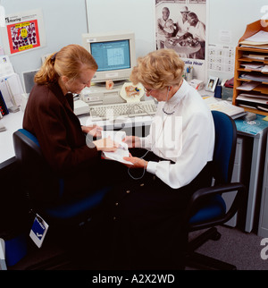 Hospital female doctor in consulting room conducting hearing test with woman patient. Stock Photo