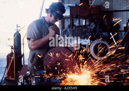 Man grinding metal strut in factory. Stock Photo