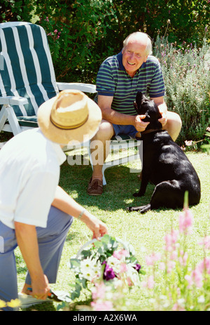 Seniors. Retired couple in their garden with their pet dog. Stock Photo