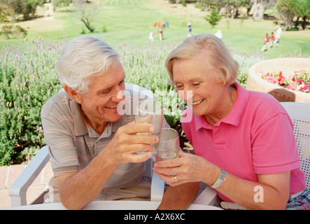 Outdoor portrait of retired couple enjoying a drink at the golf club. Stock Photo