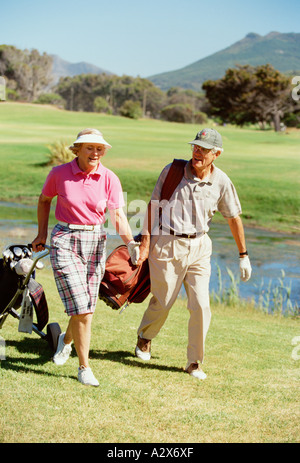 Retirement age man and woman walking together on golf course. Stock Photo
