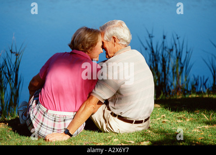 Senior couple outdoors sitting on river bank. Stock Photo