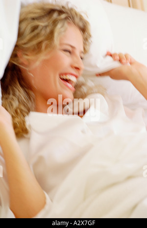 Close-up of young blond hair woman indoors in bed. Laughing. Stock Photo
