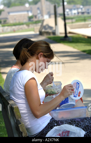 Two female office workers sitting in the park having lunch. Stock Photo