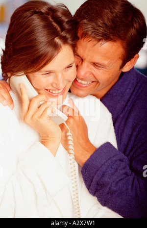 Close-up of young couple indoors talking on the telephone. Stock Photo