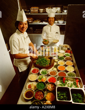 Two Asian male chefs in hotel restaurant kitchen preparing food ingredients. Stock Photo