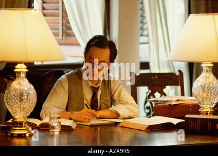 Chinese man in home office seated at desk. Stock Photo
