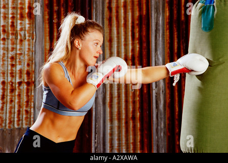 Side view indoors of a woman boxing a punch bag Stock Photo