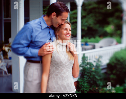 Young couple standing outside front porch of home. Stock Photo