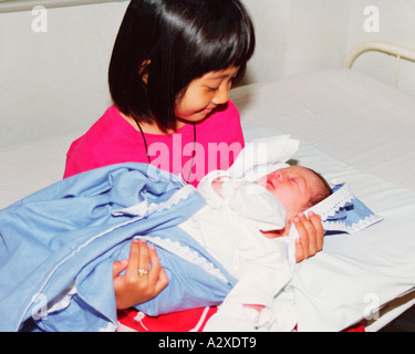Close-up indoors of proud sister holding newborn baby brother. Stock Photo