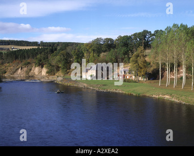 dh  RIVER TWEED BORDERS Anglers fishing from boat near river bank houses line of trees and farm Stock Photo