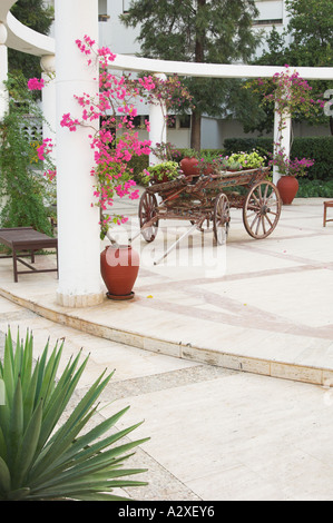 The resort courtyard decor of an old wooden wagon and bougainvillea flowers at the Jasmine Court Hotel in Girne, Cyprus Stock Photo