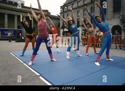 group of women doing aerobics exercise class outdoors in city square 1983 Stock Photo
