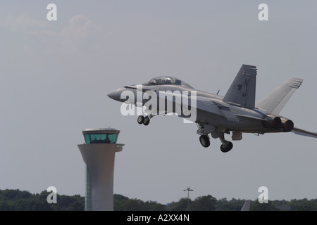 US Navy F-18F Hornet strike fighter taking off with airport air traffic control tower Stock Photo