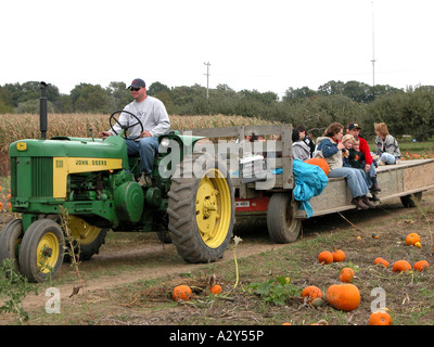 Families ride on a hay wagon in a pumpkin patch during autumn time for fun and pleasure Stock Photo