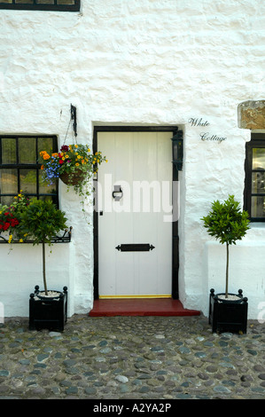 White cottage doorway in the Lancashire village of  Bolton-by-Bowland, Lancashire, England, UK, with hanging basket of flowers Stock Photo