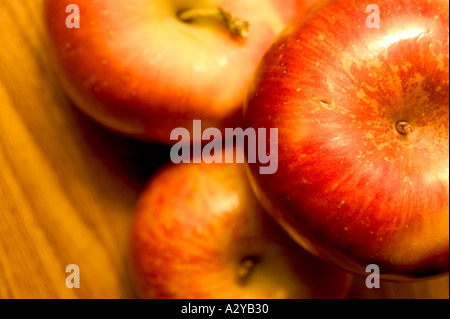 Three red apples stacked on a wood table top Stock Photo