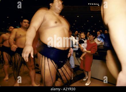 woman standing holding baby watching sumo wrestlers entering arena during contest japan Stock Photo
