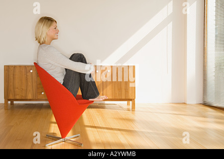 Blond woman sitting in red chair Stock Photo