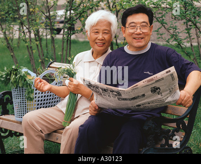 Chinese happy mature couple sitting on a bench Stock Photo