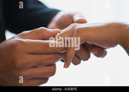 Groom placing wedding ring on brides finger Stock Photo