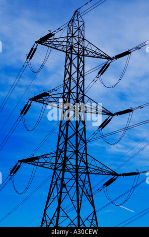 Electricity pylon silhouetted against a vivid blue sky Stock Photo