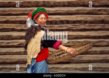 Matriarchal Mosuo woman with long house Lugu Lake Lijiang area Yunnan Province China Stock Photo