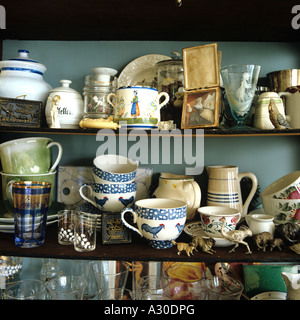 Assortment of crockery and cups on shelf in country kitchen